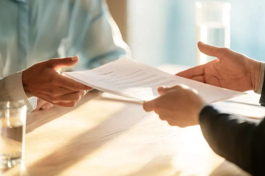 Hands exchanging a signed one-page personal loan agreement